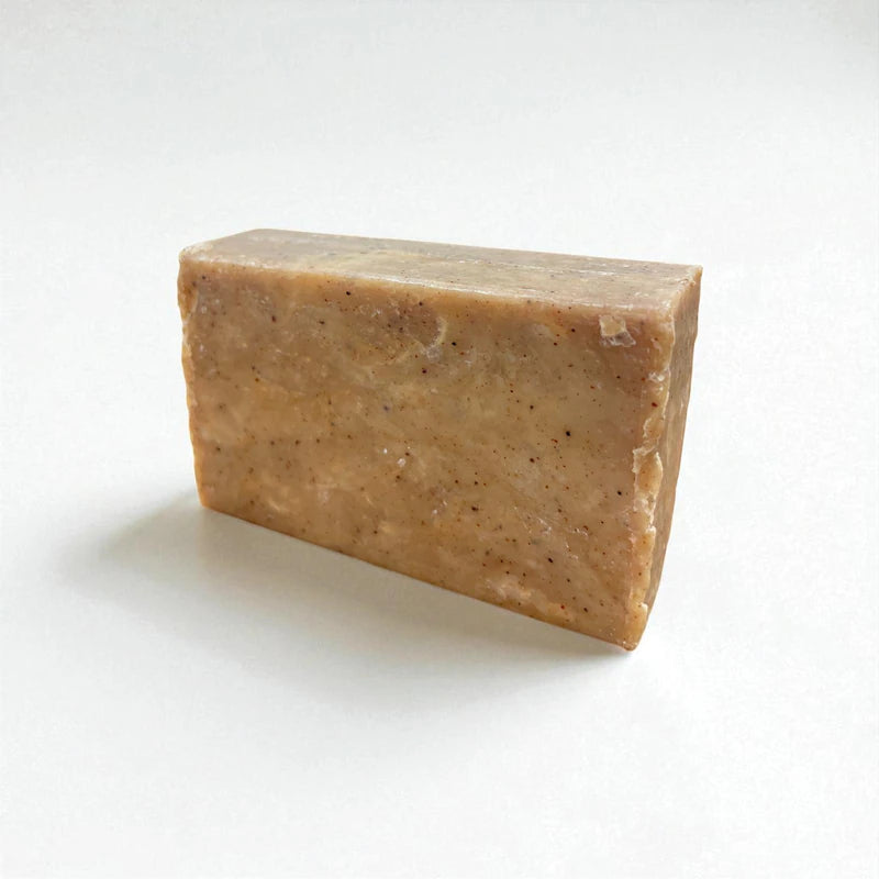 Pain rectangulaire brun clair de savon à la nigelle et à la cannelle sur fond blanc