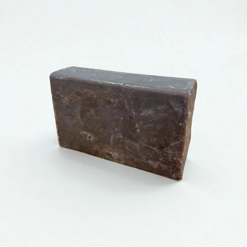 Pain rectangulaire brun de savon à la nigelle et au chocolat sur fond blanc