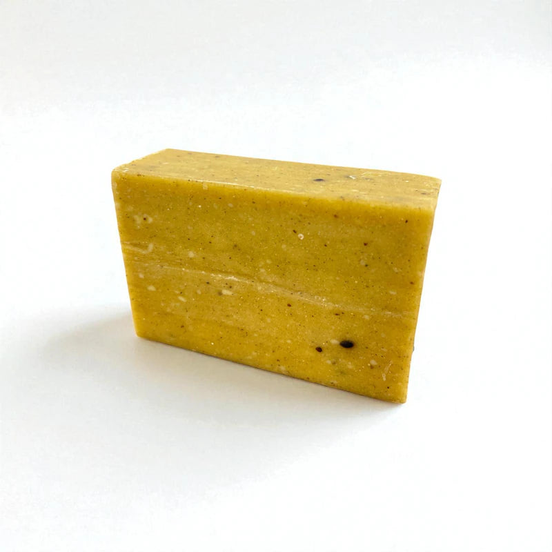 Pain rectangulaire jaune de savon à la nigelle et au soufre sur fond blanc