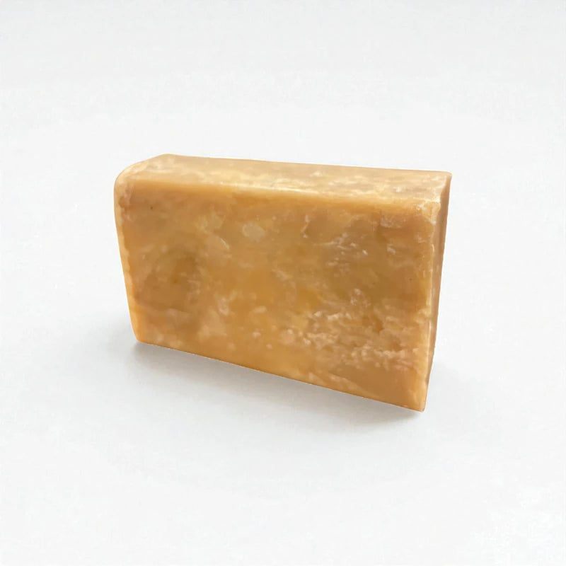 Pain rectangulaire orangé de savon à la nigelle et à la carotte sur fond blanc