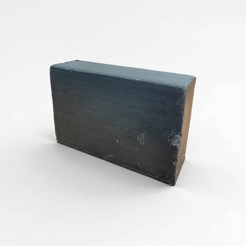 Pain rectangulaire noir de savon à la nigelle et au charbon actif sur fond blanc