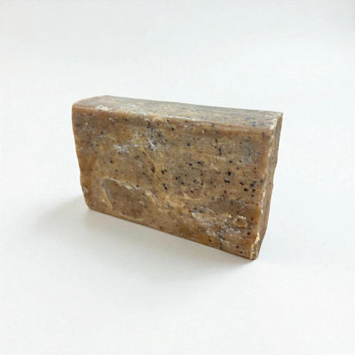 Pain rectangulaire grainé de savon à la nigelle et au café sur fond blanc