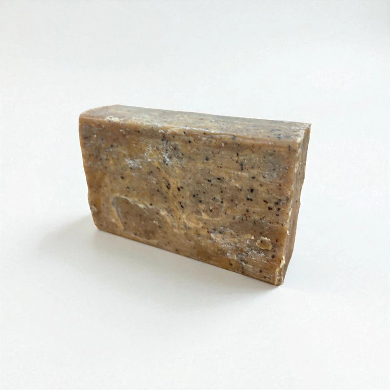 Pain rectangulaire grainé de savon à la nigelle et au café sur fond blanc