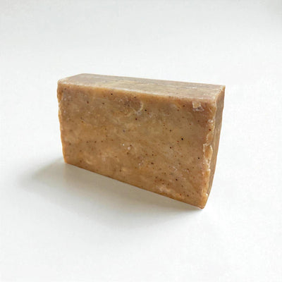 Pain rectangulaire brun clair de savon à la nigelle et à la cannelle sur fond blanc