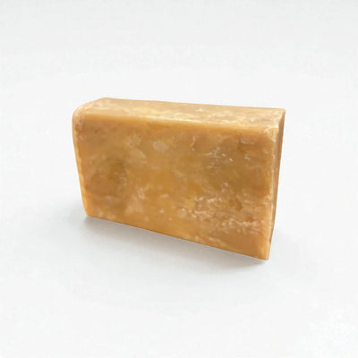 Pain rectangulaire orangé de savon à la nigelle et à la carotte sur fond blanc