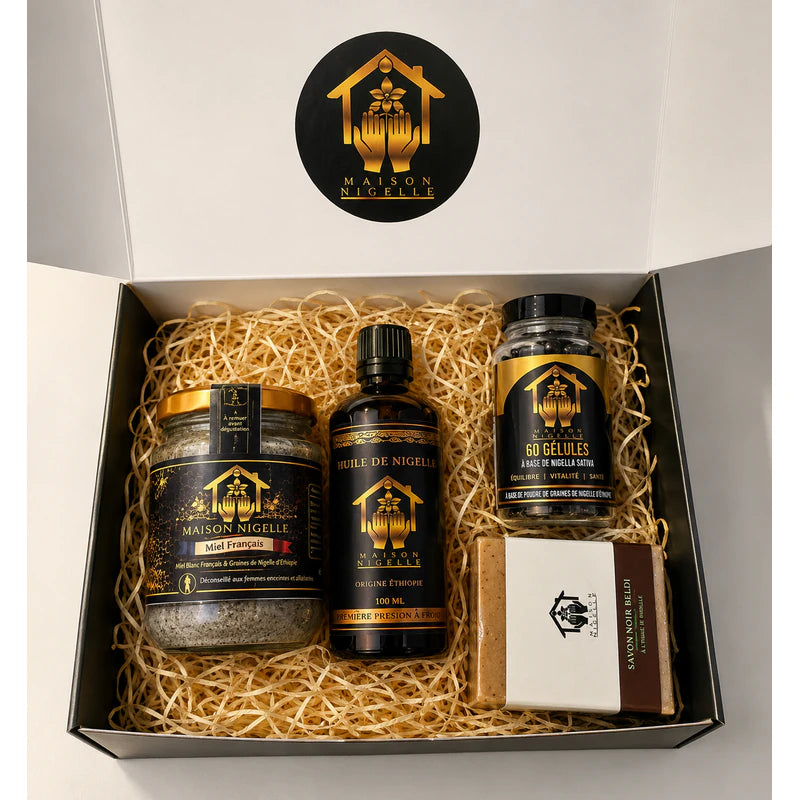 Box ouverte contenant quatre produits à la nigelle sur une garniture en papier